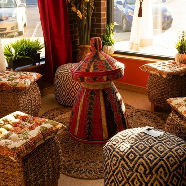Cozy restaurant corner with woven stools, floral cushions, and a colorful, traditional Ethiopian mesob.